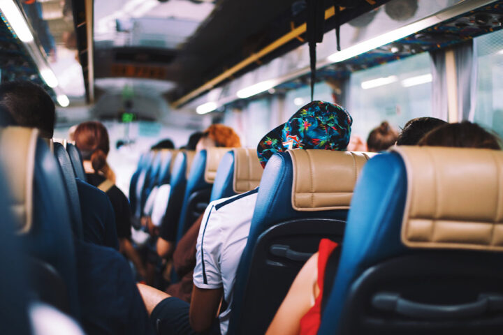 A back-to-front shot of a bus full of people in blue and tan seats