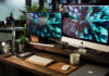 A busy desk with two computer monitors, a notebook and a MacBook