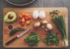 Flat lay of fresh ingredients with avocado, herbs, jalapeno, and egg